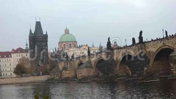 位于布拉格的老塔和大教堂绿色穹顶背景上的查尔斯桥侧视游客视频的预览图