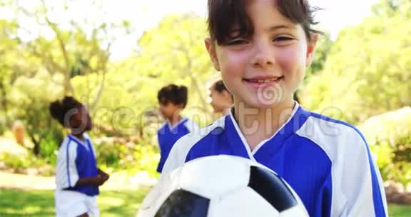 在公园里抱着足球的微笑女孩视频的预览图