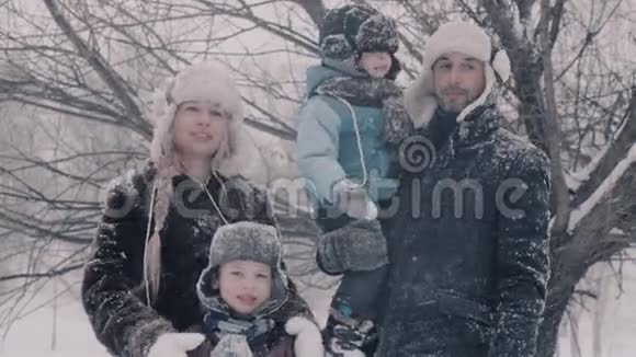 一家人站在雪下两个男孩和那里的父母视频的预览图