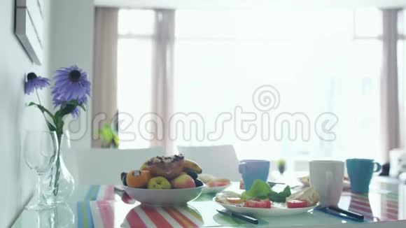 早上早餐桌上有花束盘子里有水果慢动作3840x2160视频的预览图