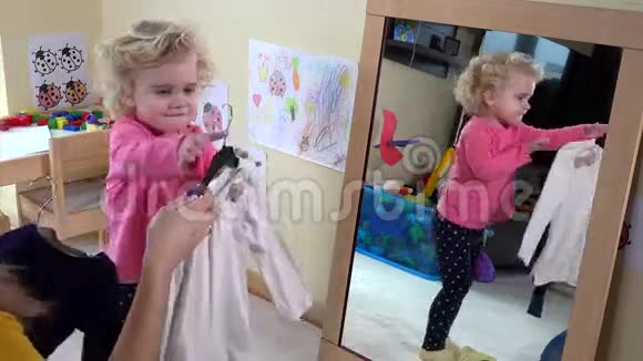 妈妈和她的小女儿在镜子前测量衣服视频的预览图