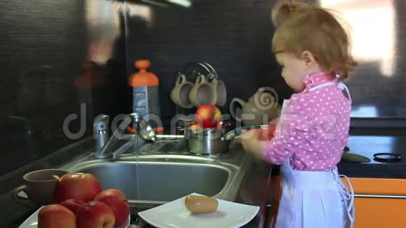 可爱的小宝宝打扮成厨师在厨房的水槽玩具里洗澡视频的预览图