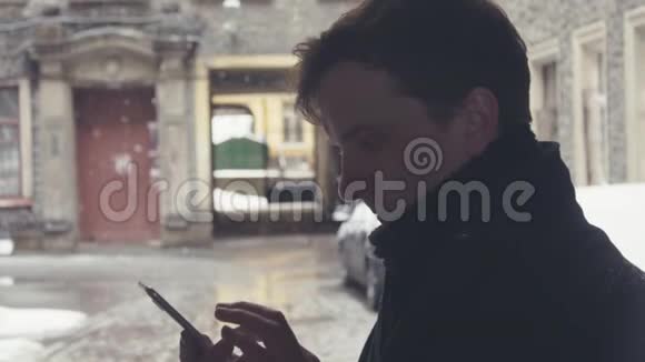 雪下街头使用智能手机编织围巾的年轻人画像视频的预览图