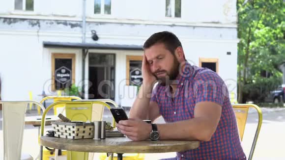 无聊昏昏欲睡的人喝咖啡浏览智能手机视频的预览图