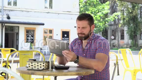 男人浏览平板电脑喝咖啡视频的预览图