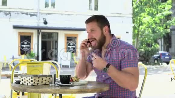 男人在早餐时用智能手机说话表现得很好视频的预览图