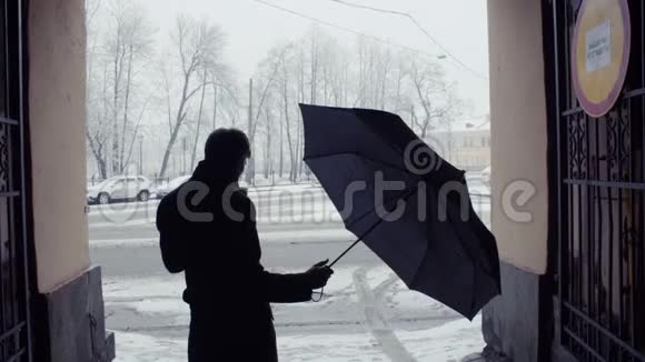 人在降雪下收伞的剪影白雪覆盖公园背景视频的预览图