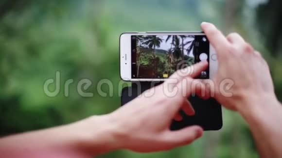 带着手机在丛林里拍照的年轻人近距离观看模糊的自然背景1920x1080视频的预览图