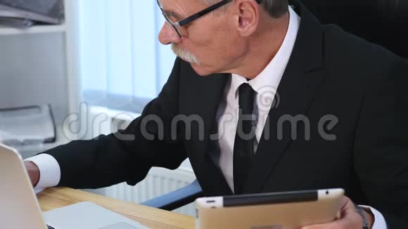 商人用手在木制桌子上的笔记本电脑上打字并做一些笔记慢动作视频的预览图