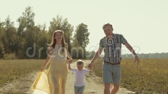 欢乐的家庭在乡间小路上奔跑手牵着儿子把他举到空中视频的预览图