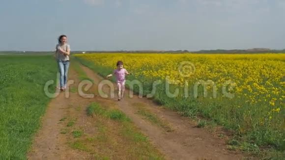 一个有孩子的女人在大自然中玩耍一个幸福的家庭正在新鲜的空气中奔跑一个带着孩子的女孩沿着一个乡村视频的预览图