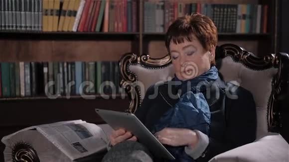 做平板电脑的老太太图书馆里有数字设备的老妇人视频的预览图