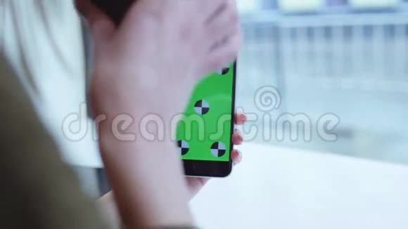 女性手拿着绿色屏幕的设备喝咖啡然后把屏幕滑起来后台的路人视频的预览图