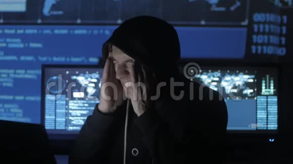 一个在电脑上工作过度的黑客在充满显示器的网络安全中心感到头疼视频的预览图