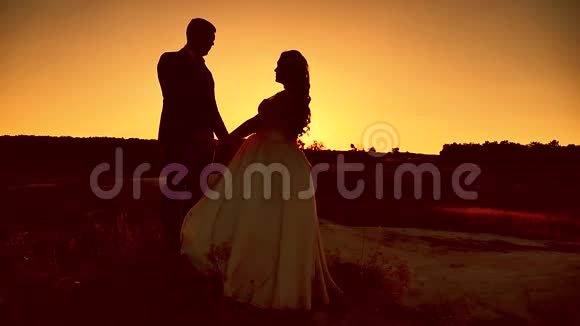 双语故事新婚夫妇面对面站在户外夕阳的背景上视频的预览图