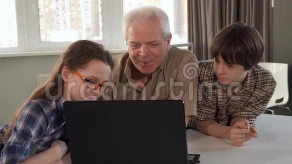 孩子们和他们的爷爷在看手提电脑视频的预览图