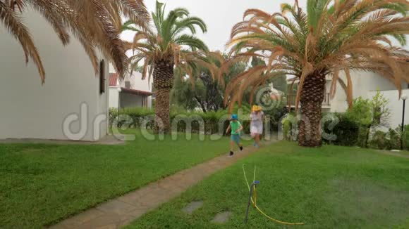 父母和孩子在雨中在院子里奔跑视频的预览图