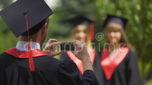 戴着毕业帽的年轻人用手机拍下最好的朋友视频的预览图