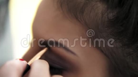 化妆师的特写镜头他的手用画笔为一个有假睫毛的模特画眉毛慢镜头视频的预览图
