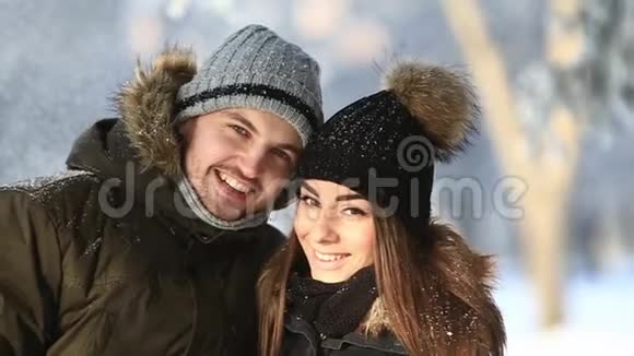快乐的一对情侣在寒假期间一起在雪地公园里玩耍近距离观看视频的预览图