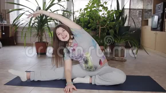 年轻孕妇在家的客厅里伸展和健身视频的预览图