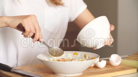 金发女人在厨房里把美味的超级食物沙拉配料和木制勺子混合在一起视频的预览图
