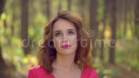 美丽少女穿着红色连衣裙在森林中健康长发的肖像秋天的快乐女人在阳光明媚的秋天公园视频的预览图
