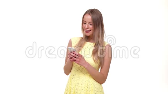 年轻积极的美女在智能手机上聊天和发短信微笑着对着灰色隔离的镜头视频的预览图