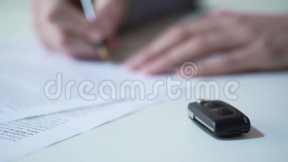 男子签署有关汽车购买或租金汽车保险服务钥匙在桌上视频的预览图