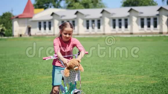 一个可爱的小女孩坐在自行车上带玩具的肖像视频的预览图