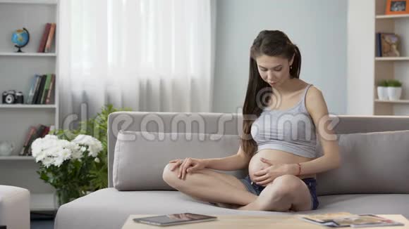 怀孕妇女坐在沙发上做怀孕瑜伽放松冥想视频的预览图