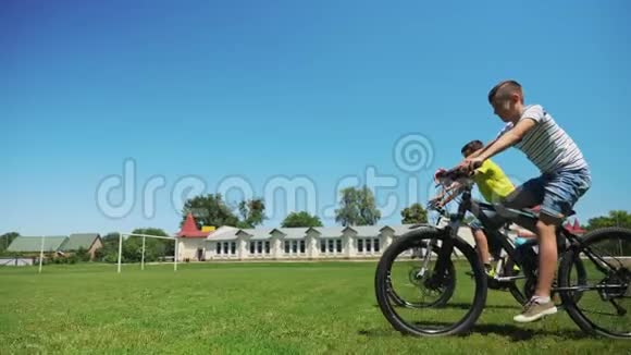 骑自行车的两个朋友一起骑在绿草地上视频的预览图