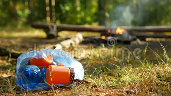 一个人在大自然中扔一个塑料瓶背景中燃烧着火户外娱乐自然和垃圾视频的预览图