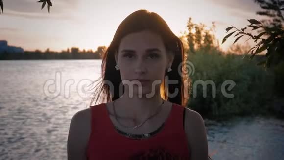 傍晚时分在池塘背景下一幅迷人的年轻女子的肖像视频的预览图