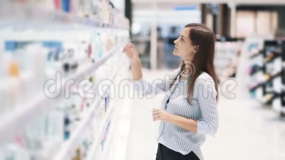 化妆品店的年轻女性选择奶油读标签慢动作视频的预览图