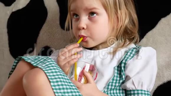 小孩坐在沙发上喝橙汁小孩看电视视频的预览图