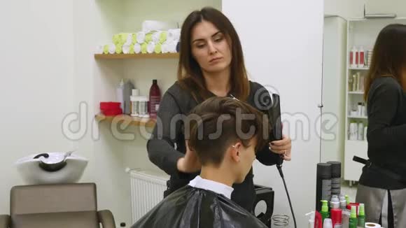 一个年轻的女人坐在理发师扶手椅上理发师做发型一个年轻的金发女人来到视频的预览图