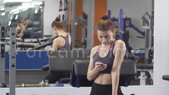 运动少女在60fps之间在健身房使用电话视频的预览图