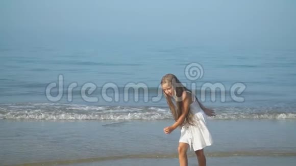 穿着白色裙子的小女孩走在海边视频的预览图