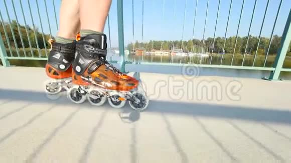 人腿在湖桥上的轻沥青路上滑冰户外在线滑冰近距离观看快速移动视频的预览图