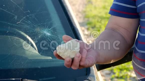 一只手拿着一块石头打碎了汽车的玻璃故意破坏视频的预览图