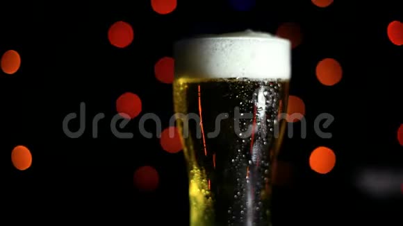 黑色背景上的一杯冷啤酒有彩灯水滴顺着玻璃流下来假日的心情视频的预览图
