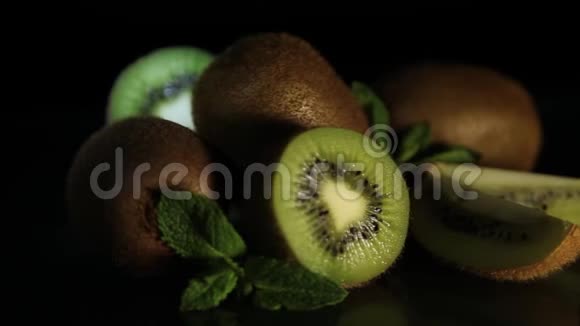 美味多汁的水果猕猴桃和薄荷放在黑桌上从桌子上反射猕猴桃高清特写视频的预览图