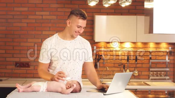 快乐的父亲在厨房的家里喂可爱的婴儿视频的预览图