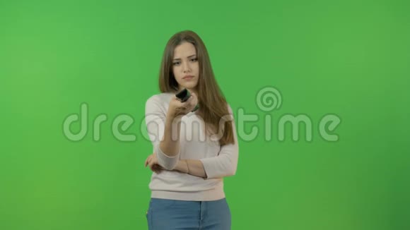 一个年轻女孩在电视遥控器上切换频道伤心坏消息在绿色的屏幕上视频的预览图