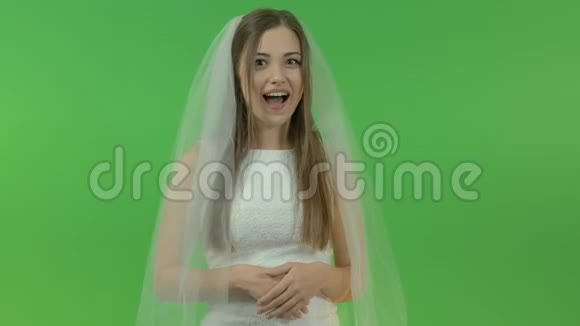 年轻的白人女孩穿着新娘礼服在绿色的背景上她手指上戴着订婚戒指视频的预览图