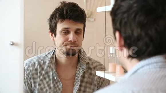 刚醒来的疲惫的男人看着镜子里的倒影看到他邋遢的样子一个格子布视频的预览图