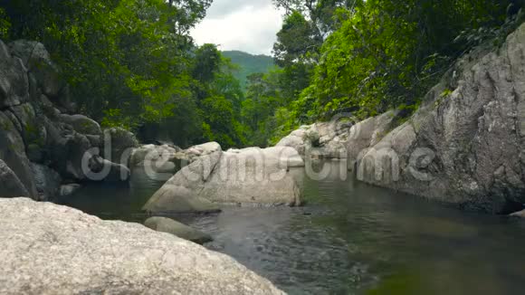 河流中的清水流在大石头和巨石之间绿色的热带森林和丛林中的石河视频的预览图