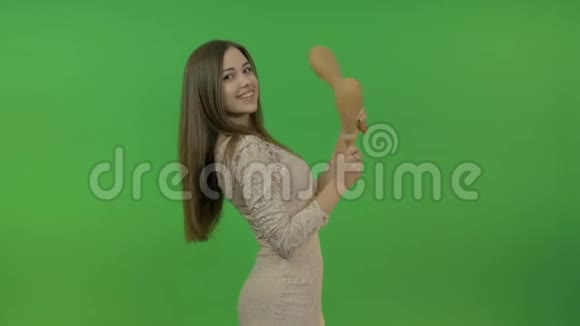 年轻美丽的女孩长发与马拉卡斯跳舞有趣又有活力在绿色的背景上视频的预览图
