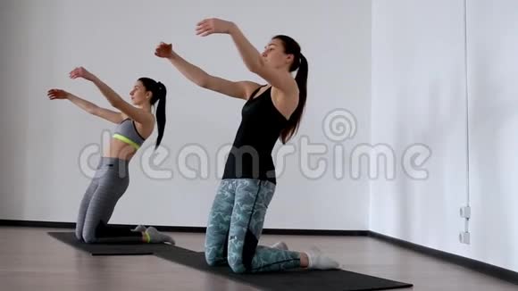 在工作室里两个女孩从事普拉提站在他们的膝盖向后训练大腿前部视频的预览图